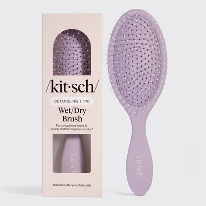 Kitsch Detangling Wet/Dry Brush in lavender, shown next to its blush pink retail packaging. Made from recycled materials, designed for smoothing knots and evenly distributing hair product.