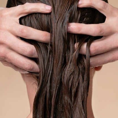 Close-up of hands running through wet hair after applying KITSCH Moisturizing Coconut Oil Conditioner