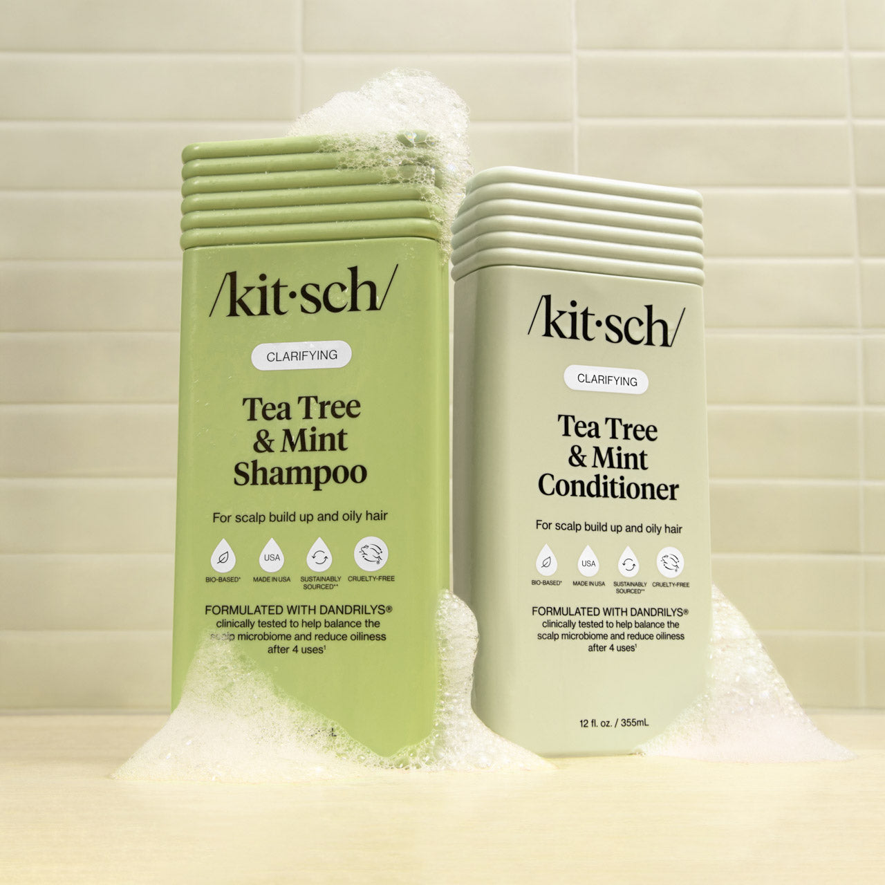 Kitsch Tea Tree & Mint Shampoo and Conditioner bottles on a tiled bathroom background