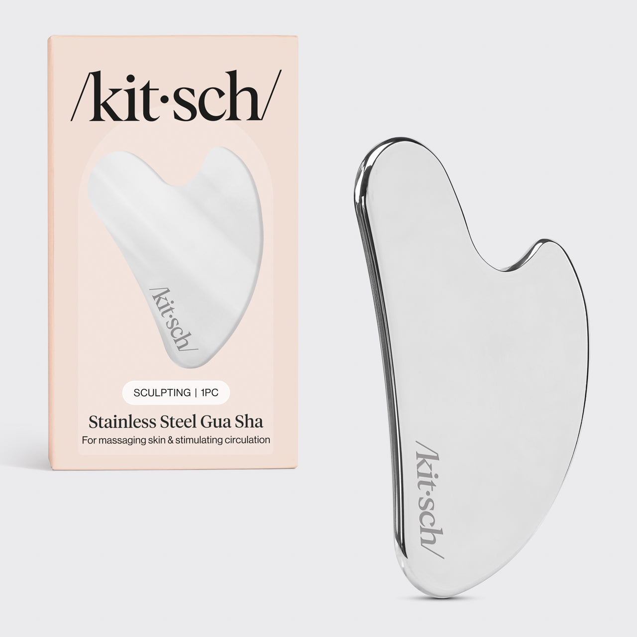 Kitsch Stainless Steel Gua Sha tool lying flat on marble surface showing curved edges