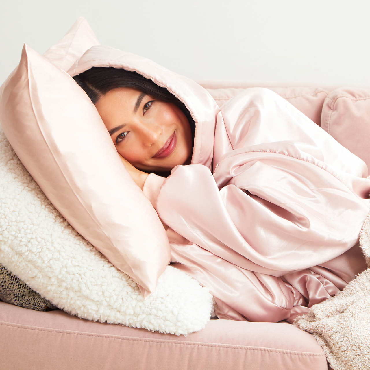 Woman sleeping comfortably in the Kitsch Glazey in Blush, designed to help protect hair overnight and reduce frizz.