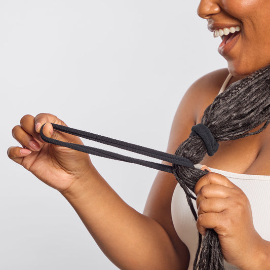 Smiling model with dreadlocks stretching Kitsch Recycled Nylon Thick Elastic in Black